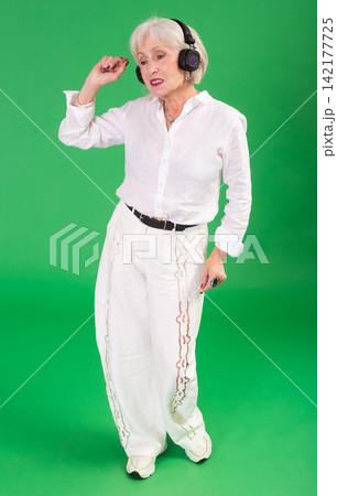 Elderly woman listening to music and dancing in front of green screen 142177725