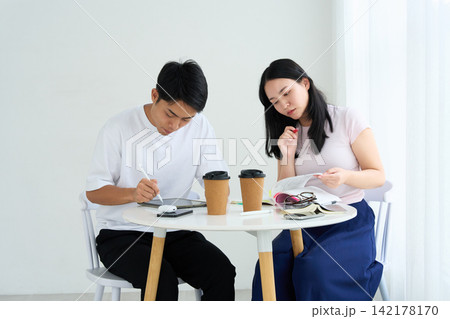 タブレットPCとテキストを使って勉強する男女 タブレットPCとテキストを使って勉強する男女 142178170