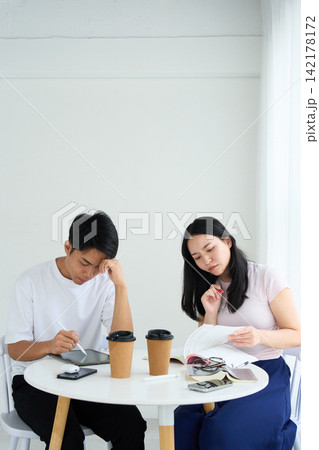 タブレットPCとテキストを使って勉強する男女 タブレットPCとテキストを使って勉強する男女 142178172