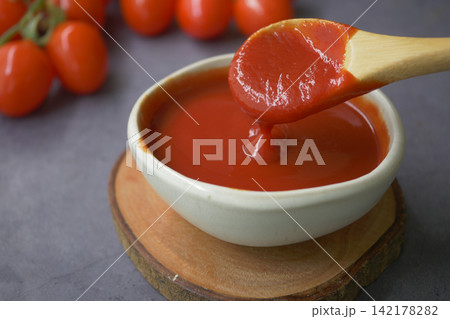 Tomato sauce in a bowl with a wooden spoon Tomato sauce in a bowl with a wooden spoon 142178282