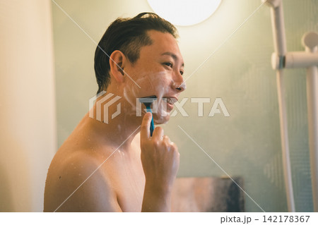 シャワー中に笑顔でひげを剃る男性のバスタイム 142178367