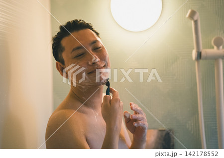 目を閉じて笑顔でひげを剃る男性のバスタイム 142178552