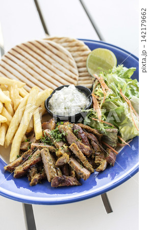 sliced grilled lamb chop with fries and Tzatziki in greek outdoor cafe sliced grilled lamb chop with fries and Tzatziki in greek outdoor cafe 142179662