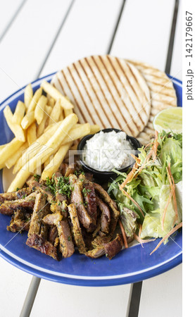 sliced grilled lamb chop with fries and Tzatziki in greek outdoor cafe 142179667
