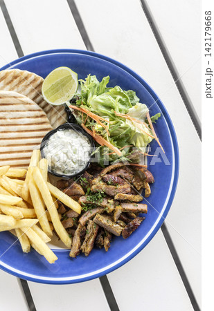 sliced grilled lamb chop with fries and Tzatziki in greek outdoor cafe sliced grilled lamb chop with fries and Tzatziki in greek outdoor cafe 142179668