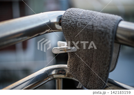 Gray, textured towel draped over a chrome metal railing with a small white plastic clothespin 142183159