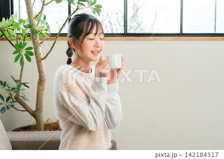 自宅のリビングでホットドリンクを飲む小学生,中学生の女の子 自宅のリビングでホットドリンクを飲む小学生,中学生の女の子 142184317