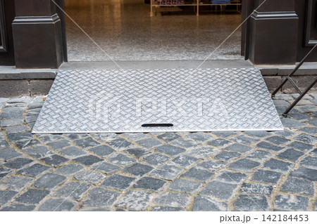 Open door in the shop with desent for the disabled in big city. Building entrance with ramp for wheelchair people. Open door in the shop with desent for the disabled in big city. Building entrance with ramp for wheelchair people. 142184453