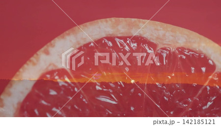 Displaying halved grapefruit showing translucent pulp and rind in studio, with sunset horizon Displaying halved grapefruit showing translucent pulp and rind in studio, with sunset horizon 142185121