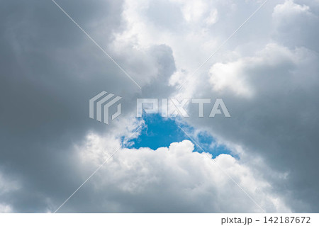厚い雲の切れ間から青空と光が見えるドラマチックな空 厚い雲の切れ間から青空と光が見えるドラマチックな空 142187672