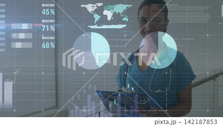 Standing clinician in blue scrubs with stethoscope holding tablet with pen in clinic with HUD data 142187853