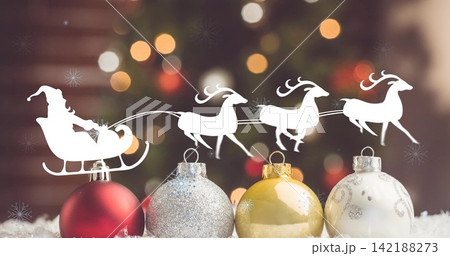 Showing four Christmas baubles resting on fake snow at home, with Santa sleigh and reindeer cutout Showing four Christmas baubles resting on fake snow at home, with Santa sleigh and reindeer cutout 142188273