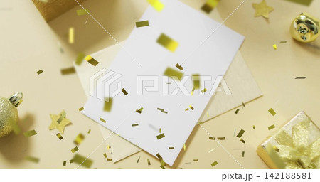 Resting blank white card sitting on cream envelope on beige tabletop, with falling gold confetti Resting blank white card sitting on cream envelope on beige tabletop, with falling gold confetti 142188581