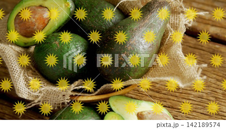 Displaying cluster of ripe avocados resting in burlap basket on wooden table, yellow starbursts Displaying cluster of ripe avocados resting in burlap basket on wooden table, yellow starbursts 142189574