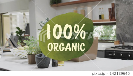 Displaying 100% ORGANIC label overlaying island counter in modern kitchen, with potted herbs 142189640