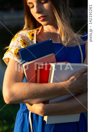Woman holding stack of books in hands in green park. Book lover day celebration. Self education and digital detox concept 142191261
