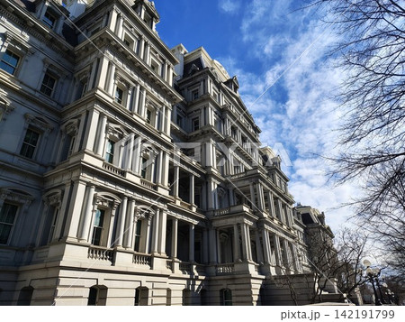 A historic government building in the Second Empire style. The massive gray facade is decorated with numerous columns, arched windows, and cornices. 142191799