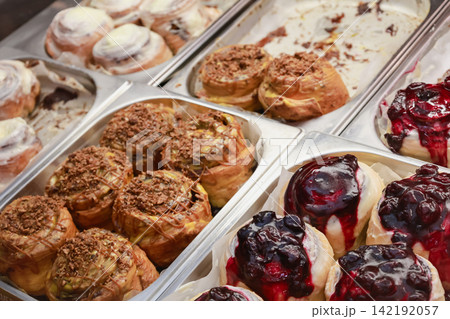 Cinnabons in showcase. Cinamon buns in Cinnamon rolls with nuts and fruits, isolated. Sweet dessert variaty. Fresh bakery in cafe. Decorated muffins in restaurant. Sweet breakfast conept. Cinnabons in showcase. Cinamon buns in Cinnamon rolls with nuts and fruits, isolated. Sweet dessert variaty. Fresh bakery in cafe. Decorated muffins in restaurant. Sweet breakfast conept. 142192057