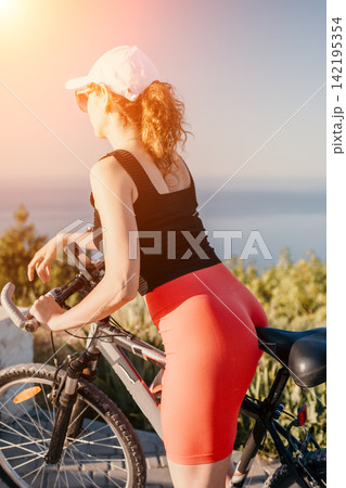 Cyclist woman bicycle outdoor lifestyle exercise activity relaxing on a summer day overlooking the sea with copy space Cyclist woman bicycle outdoor lifestyle exercise activity relaxing on a summer day overlooking the sea with copy space 142195354