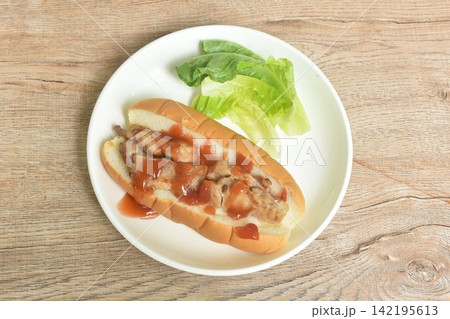 hot dog stuffed grilled pork with lettuce dressing ketchup with cos lettuce salad on dish hot dog stuffed grilled pork with lettuce dressing ketchup with cos lettuce salad on dish 142195613