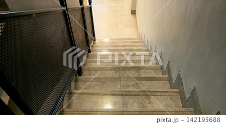 Modern interior staircase with anti-slip tiles and black mesh railings. Modern interior staircase with anti-slip tiles and black mesh railings. 142195688