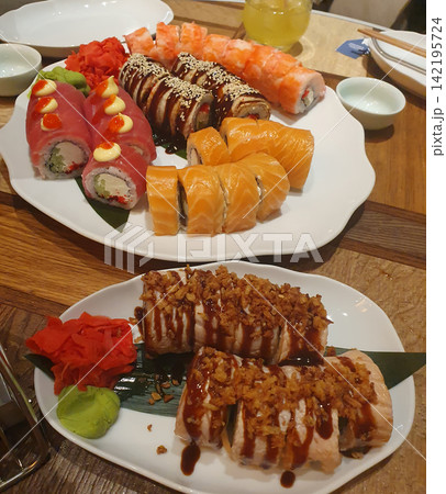 Large set of assorted sushi and rolls with salmon, tuna, eel, wasabi and ginger on white plates. Asian cuisine, sushi bar Large set of assorted sushi and rolls with salmon, tuna, eel, wasabi and ginger on white plates. Asian cuisine, sushi bar 142195724