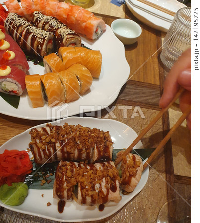 Large set of assorted sushi and rolls with salmon, tuna, eel, wasabi and ginger on white plates. Asian cuisine, sushi bar Large set of assorted sushi and rolls with salmon, tuna, eel, wasabi and ginger on white plates. Asian cuisine, sushi bar 142195725