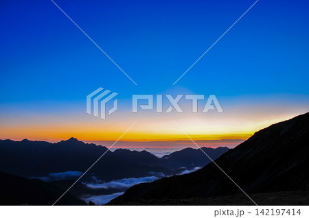 秋の夕暮れ 唐松岳から望むグラデーションの美しい夕空と猫又山に沈みゆく太陽の風景 142197414