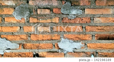 Weathered red brick wall with peeling cement plaster texture. 142198189