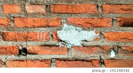 Damaged red brick wall with cement patches. Damaged red brick wall with cement patches. 142198192