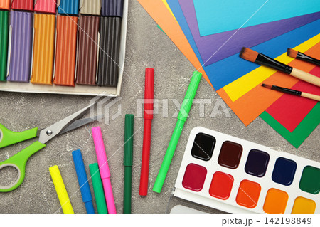 School supplies stationery: plasticine, color paper, paints on grey concrete background, Back to school concept. School supplies stationery: plasticine, color paper, paints on grey concrete background, Back to school concept. 142198849