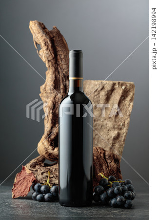 Bottle of red wine with stone, dried snags, and blue grapes. Bottle of red wine with stone, dried snags, and blue grapes. 142198994