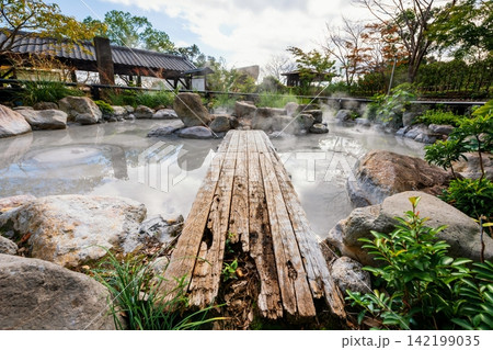 Oniishibozu Jigoku hot spring in autumn colors against blue sky, Beppu 142199035