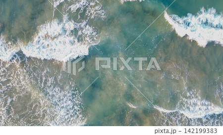 Top down aerial drone view of turquoise ocean water surface with white foam splashing waves for aquatic backdrop stock photo 142199383