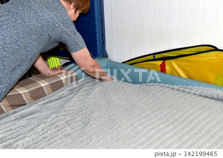 A woman makes her bed. A woman makes her bed. 142199465
