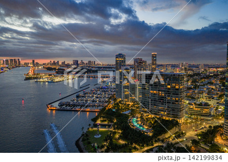 Twilight over Miami skyline and marina. Luxury yachts glowing in the Miami harbor. Sunset cruise near Miami downtown skyscrapers. Aerial night view of Miami Beach at dusk. Twilight over Miami skyline and marina. Luxury yachts glowing in the Miami harbor. Sunset cruise near Miami downtown skyscrapers. Aerial night view of Miami Beach at dusk. 142199834