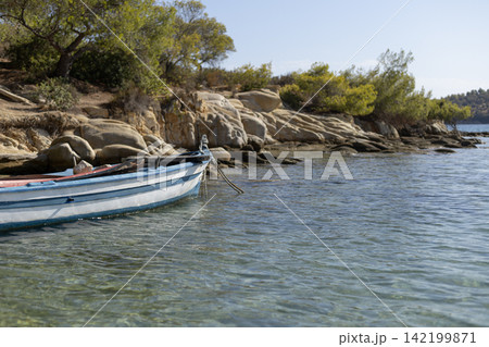 Blue wooden rowboat on rocky mediterranean coast 142199871