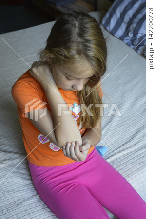 A beautiful young woman in casual clothing is holding her elbow A beautiful young woman in casual clothing is holding her elbow 142200778