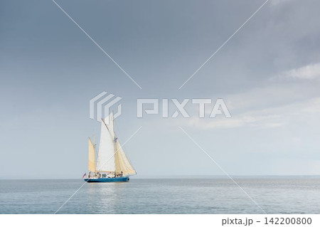 Ancient sail ship, magic reflections on water surface, sailing regatta in the Gulf of Finland at sunny day, Yachtsmen are sitting amicably on board of the sailing boat, teamwork Ancient sail ship, magic reflections on water surface, sailing regatta in the Gulf of Finland at sunny day, Yachtsmen are sitting amicably on board of the sailing boat, teamwork 142200800