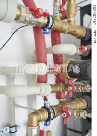 Water pipes, brass fittings, valves and circulation equipment in a home utility room Water pipes, brass fittings, valves and circulation equipment in a home utility room 142200803