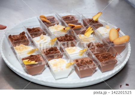 chocolate desserts arranged on a plate in a kitchen counter with whipped cream and fruit slices, delicious and inviting top-down perspective, brown and white colors, commercial food display. chocolate desserts arranged on a plate in a kitchen counter with whipped cream and fruit slices, delicious and inviting top-down perspective, brown and white colors, commercial food display. 142201525