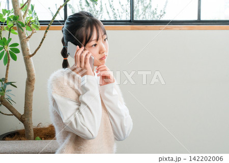 自宅のソファに座りスマホで通話する小学生,中学生の女の子 自宅のソファに座りスマホで通話する小学生,中学生の女の子 142202006