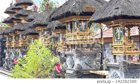 Pura Besakih temple complex showcases a row of ancient Balinese shrines with traditional thatched roofs and elaborately carved golden details 142202380