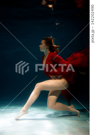 Aquatic ballet portrait. Graceful swimmer with elegant pose underwater Aquatic ballet portrait. Graceful swimmer with elegant pose underwater 142202490