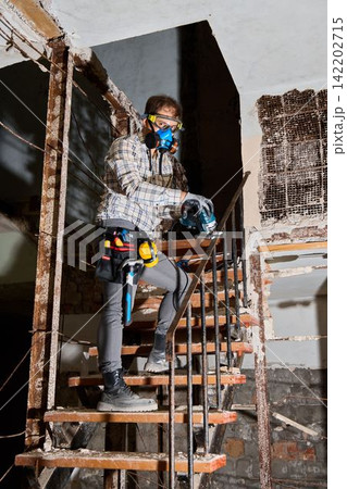 Worker Using Power Tool on Corroded Staircase in Dilapidated Building Worker Using Power Tool on Corroded Staircase in Dilapidated Building 142202715