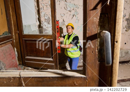 Contractor surveying dilapidated interior through doorway 142202729