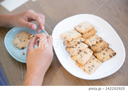 手作りの米粉チョコチップクッキーを食べる子ども 手作りの米粉チョコチップクッキーを食べる子ども 142202920