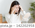 髪の毛の生え際を鏡でチェックする女性 142202958