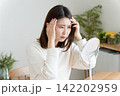 髪の毛の生え際を鏡でチェックする女性 142202959