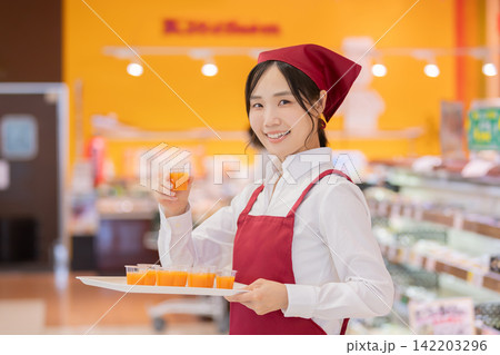 スーパーマーケットで試飲用ドリンクを提供する女性スタッフ スーパーマーケットで試飲用ドリンクを提供する女性スタッフ 142203296